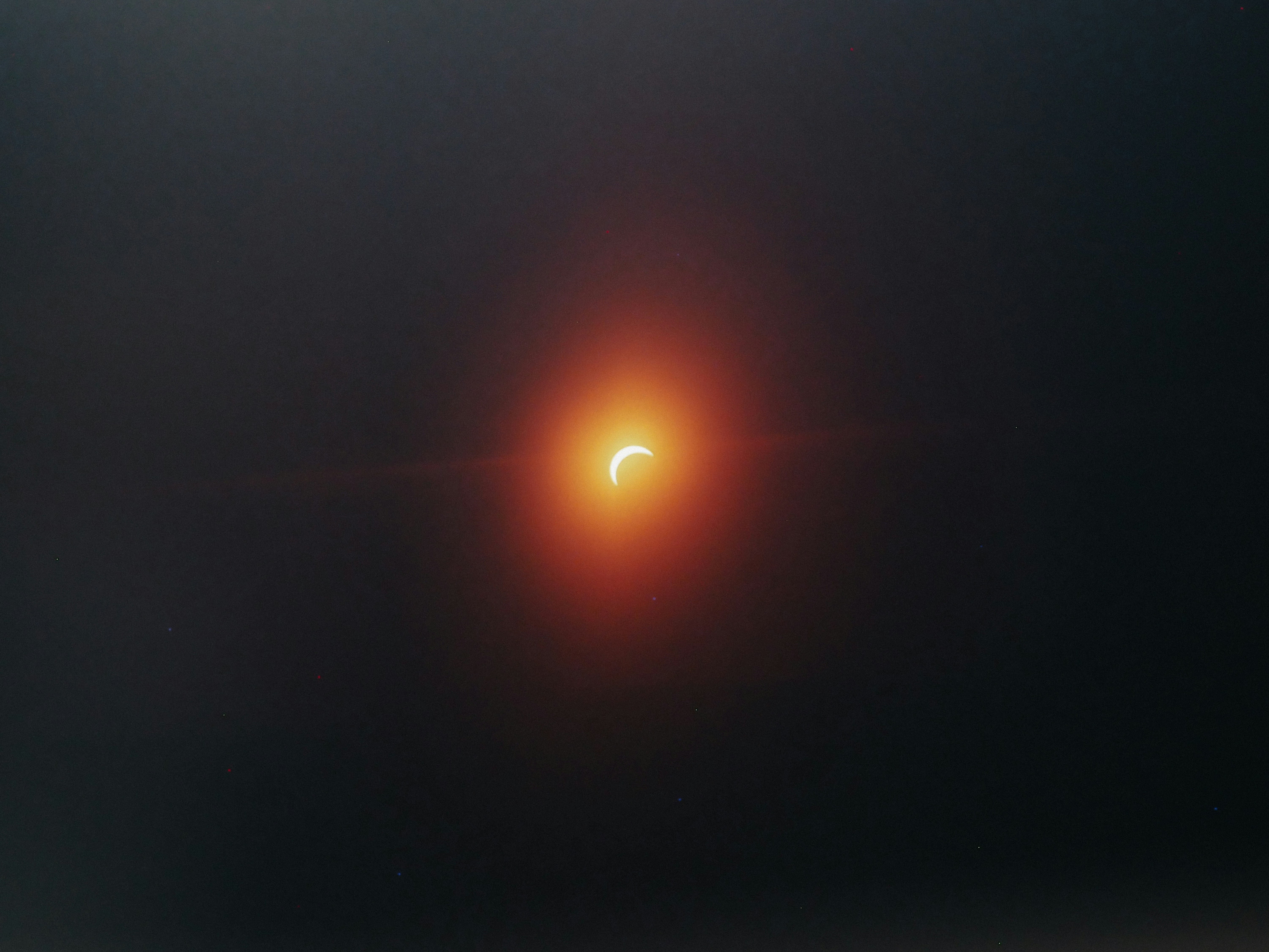A crescent eclipse glowing through dark clouds